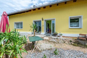 Ein gelbes Gebäude mit einer Terrasse, einem Tisch und einer Bank.