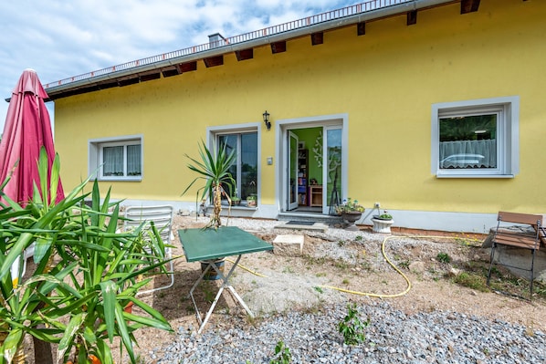 Un bâtiment jaune doté d’un patio, d’une table et d’un banc.