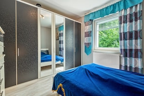 A bedroom with a bed, wardrobe, and a window with curtains.