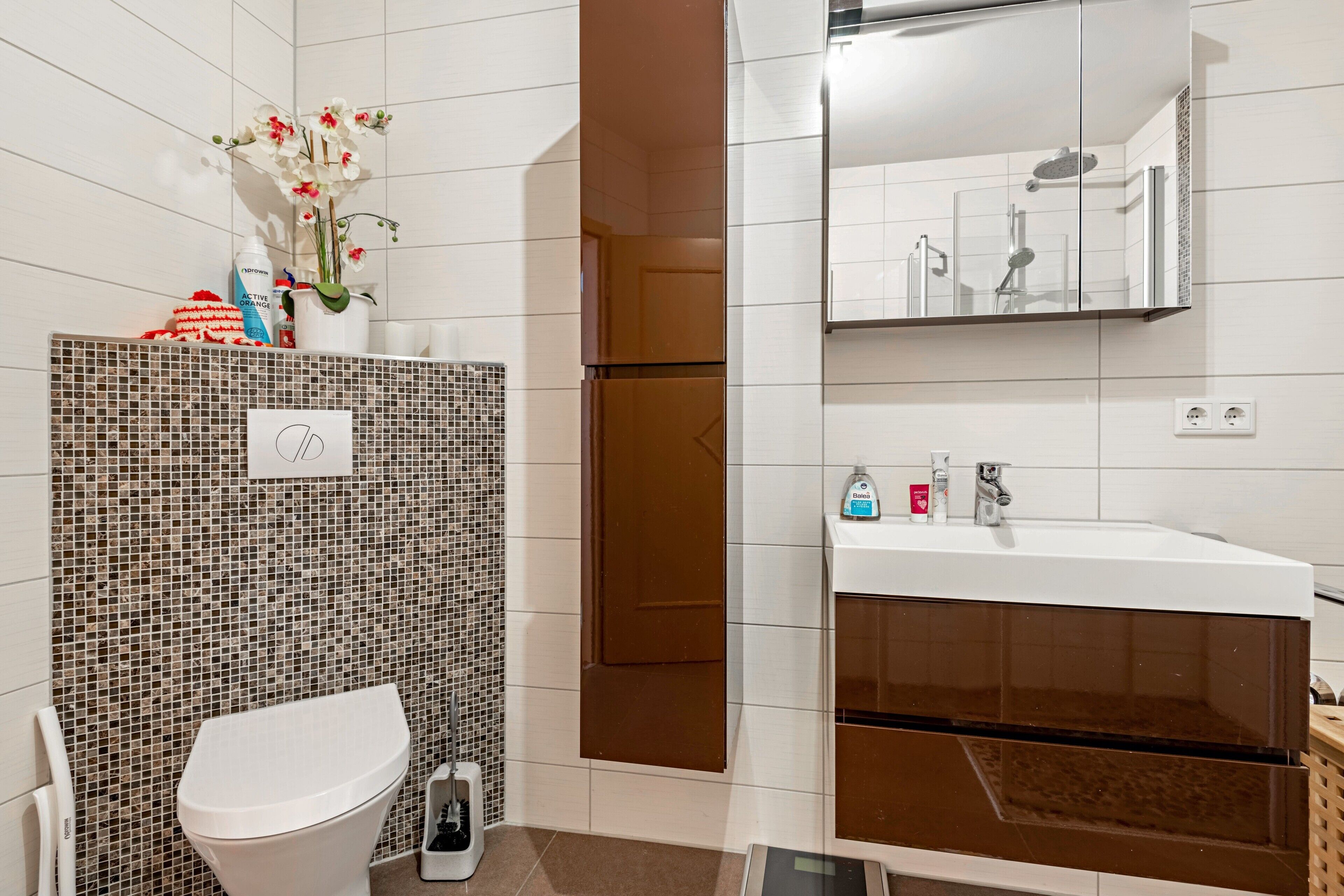 A bathroom with a toilet, a sink, a shower, and a mirror.
