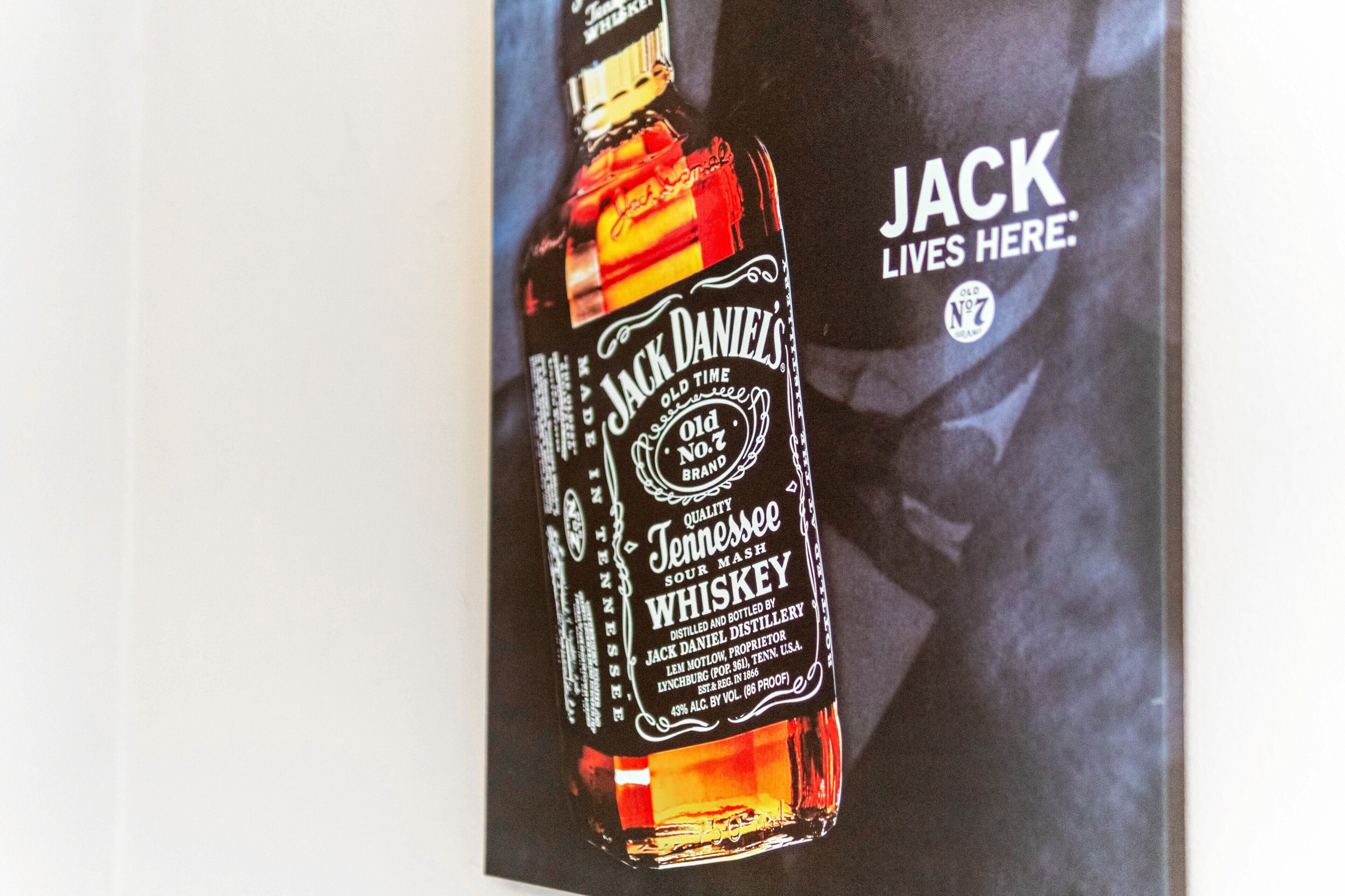 A Jack Daniel's whiskey bottle with a label and a partial view of a person in the background.