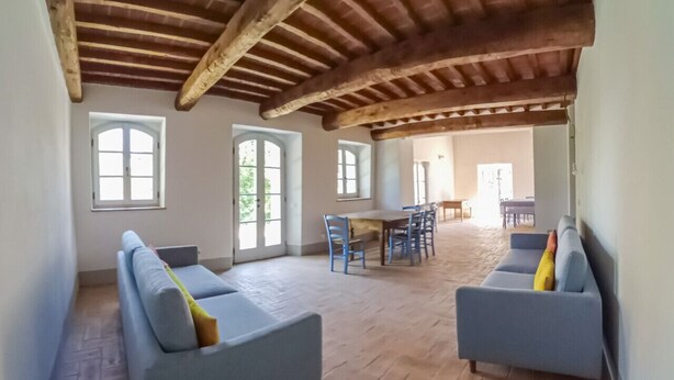Una habitación amplia con dos sofás azul claro, techo de madera y un comedor con sillas.
