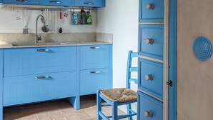 Una cocina con armarios azules, un lavabo y una silla.