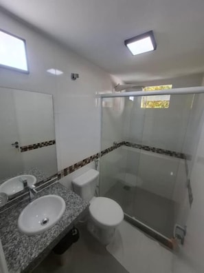Ein Badezimmer mit einer Duschkabine, einem Waschbecken und einer Toilette.