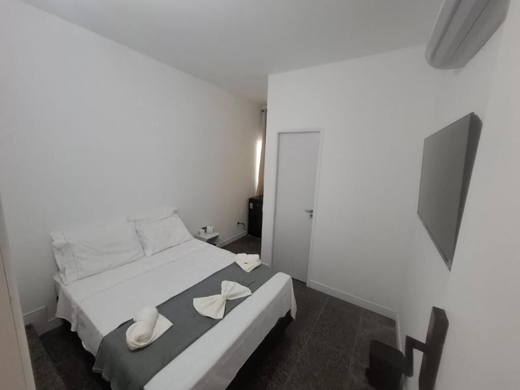 A hotel room with a bed, a bedside table, a TV, and a door.