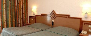 A hotel room with two beds, a wooden headboard, bedside lamps, a telephone, and a curtain with a leaf pattern. - Royal Azur Thalassa (Hammamet)