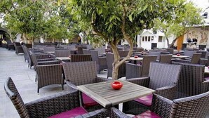 An outdoor seating area with wicker furniture and a small table with a red object on it. - Royal Azur Thalasso Golf (Hammamet)