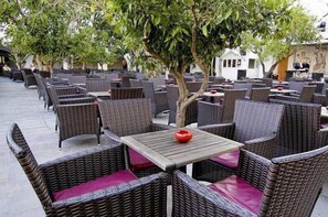 An outdoor seating area with wicker furniture and a small table with a red object on it. - Royal Azur Thalasso Golf (Hammamet)