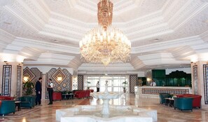 A grand lobby with a large chandelier, a fountain, and a reception desk. - Royal Azur Thalasso Golf (Hammamet)