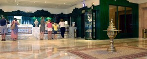 A lobby with a reception desk, a green wall, and a large ornate lamp. - Royal Azur Thalasso Golf (Hammamet)