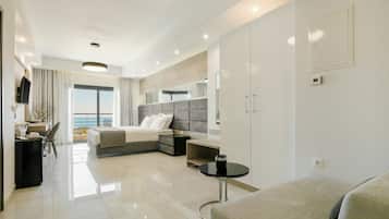 Habitación de hotel moderna con cama, sofá, escritorio y vista al mar.
