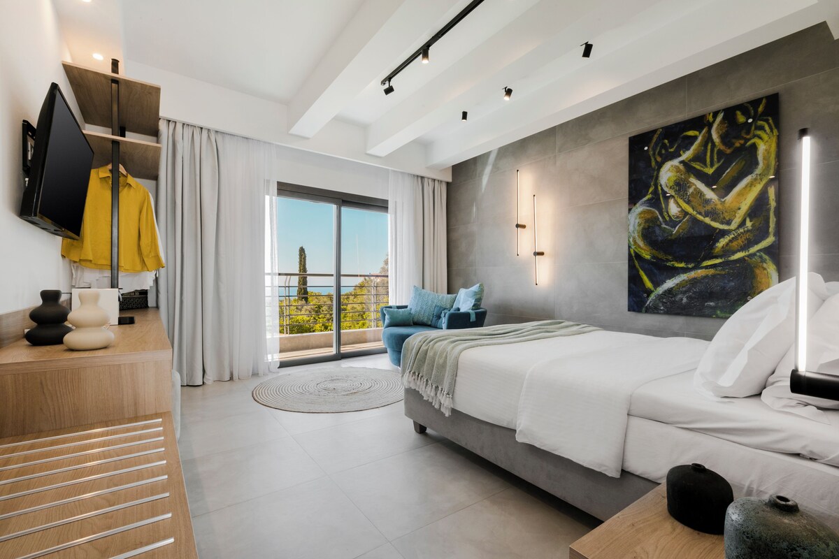 Quarto moderno com cama, televisão, varanda com vista e um quadro na parede.