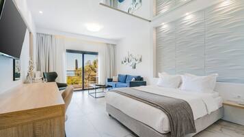 Ein modernes Hotelzimmer mit einem großen Bett, einem Schreibtisch, einer Sitzecke und einem Balkon mit Blick.
