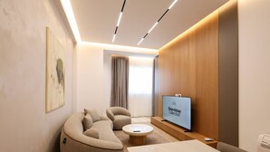 Un soggiorno moderno con un divano componibile, un tavolino, una TV a schermo piatto e un tavolo da pranzo.