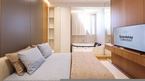 Una camera d'hotel moderna con un letto, una televisione, un bagno con una vasca e un grande specchio.