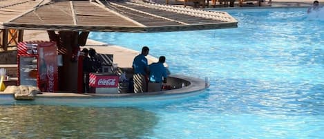 Zona de piscina con sillones de descanso, refrigerador de Coca-Cola y un bote pequeño.