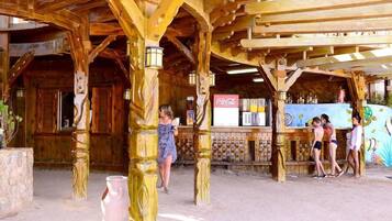 A wooden structure with a rustic design, a Coca-Cola refrigerator, and a mural on the wall.