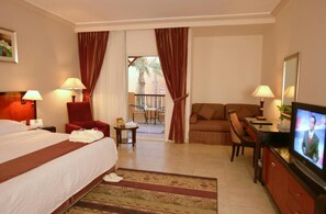 A hotel room with a bed, a TV, a sofa, and a dining area. - Rehana Royal Beach Resort (Sharm El Sheikh)