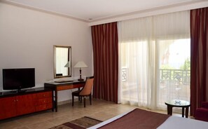 A hotel room with a television, desk, chair, and a large window with curtains. - Rehana Royal Beach Resort (Sharm El Sheikh)