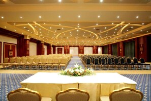 A conference room with rows of chairs, a long table with a floral centerpiece, and a stage area. - Rehana Royal Beach Resort (Sharm El Sheikh)