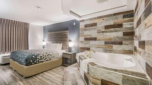 A hotel room with a bed, bedside table, lamp, and a bathtub. - Econo Lodge Inn & Suites Des Moines - Merle Hay Rd (Des Moines)