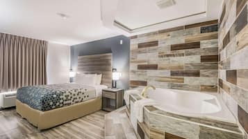 Ein Hotelzimmer mit Bett, Nachttisch, Lampe und einer Badewanne.