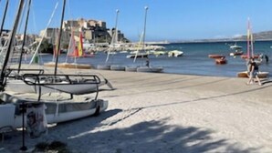 A marina with boats docked, a sandy beach, and a clear blue sky. - Calvi plage T3 (Calvi)