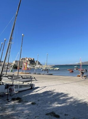 A marina with boats docked, a sandy beach, and a clear blue sky. - Calvi plage T3 (Calvi)