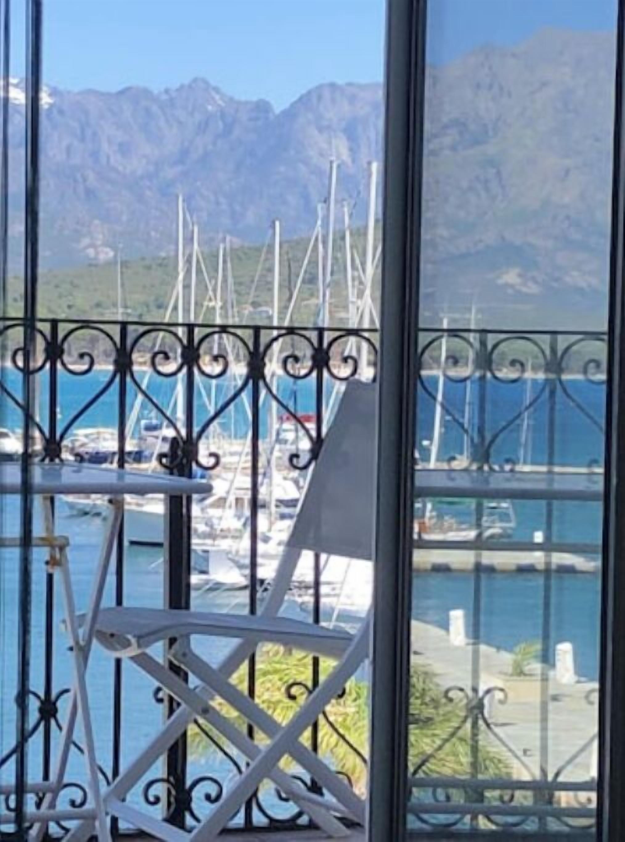 Un balcón con vistas a un puerto deportivo y montañas.