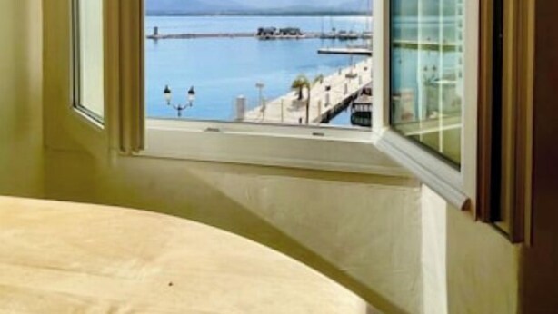 A room with a large window overlooking a marina and mountains. - Calvi plage T3 (Calvi)