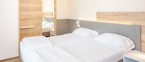 Habitación de hotel con cama, mesita de noche, armario y espejo.