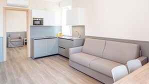 Ett modernt kök med mikrovågsugn, diskho och en liten matplats med bord och stolar.