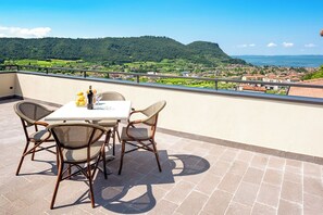 A terrace with a table and chairs, a bottle of wine, and a glass of wine. - Residence Panorama (Suzzara)