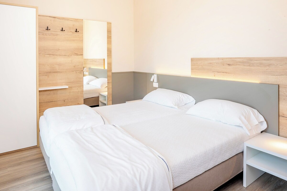 Ein Hotelzimmer mit Bett, Nachttisch, Kleiderschrank und Spiegel.