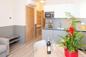 Une cuisine moderne équipée d’un four à micro-ondes, d’un évier et d’un coin repas avec une table, des chaises et une bouteille de vin.