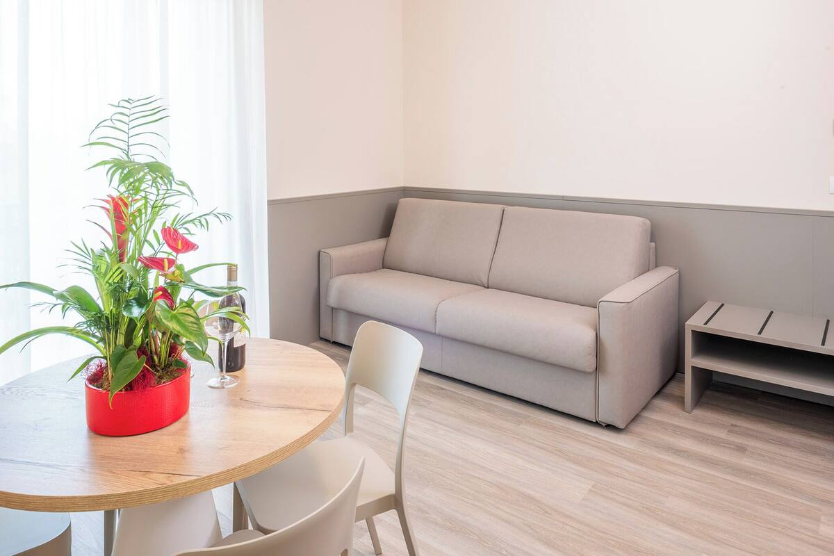A modern living room with a round wooden table, a beige sofa, and a potted plant.