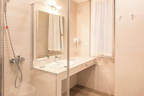 A modern bathroom with a glass-enclosed shower, a white sink, and a mirror with lights. - Residence Panorama (Suzzara)
