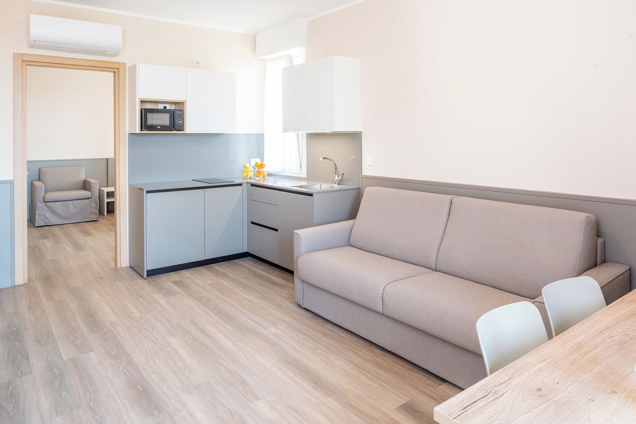 A modern kitchen with a microwave, sink, and a small dining area with a table and chairs.
