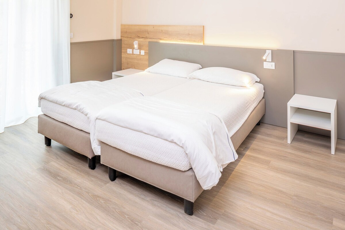 Ein modernes Schlafzimmer mit einem großen Bett, Nachttischen und einem Kopfteil mit integrierter Beleuchtung.