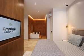 Une chambre d’hôtel moderne comprenant un lit, un coin salon et une salle de bain.