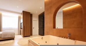 Une salle de bain moderne avec une grande baignoire, un mur miroir et une porte en bois.