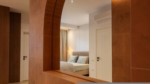 Una camera da letto moderna con un letto, un comodino e uno specchio che riflette l'ambiente.