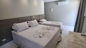 Habitación de hotel con dos camas, piso de mármol, una mesita y una lámpara en el techo.