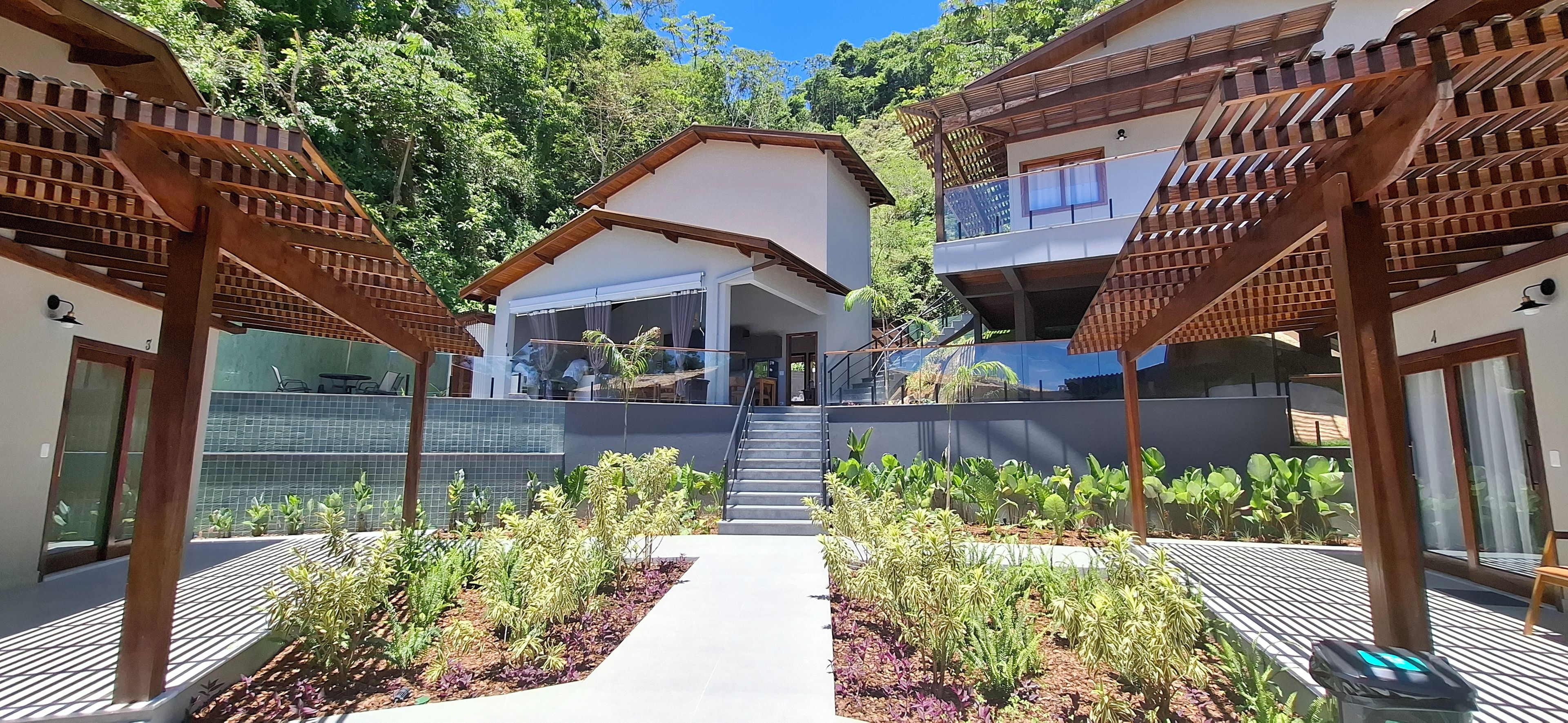 Un edificio moderno con una entrada central, rodeado de un jardín con diversas plantas.