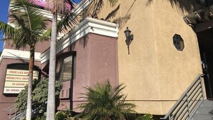 A building with a sign for 'DRIMAS' and a sign for 'FREE LAX SHUTTLE WHIRLPOOL SAUNTER IN ROOM SERVICE HI-SPEED INTERNET.' - Crimson Hotel (Manhattan Beach)