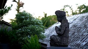 En statue af en siddende figur i en have.