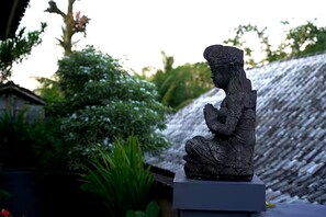 Eine Statue einer sitzenden Figur in einem Garten.