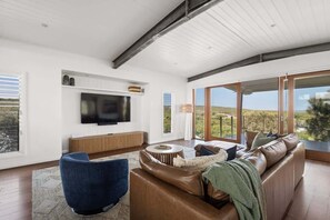 A modern living room with a leather sofa, a blue armchair, and a flat-screen TV mounted on the wall.