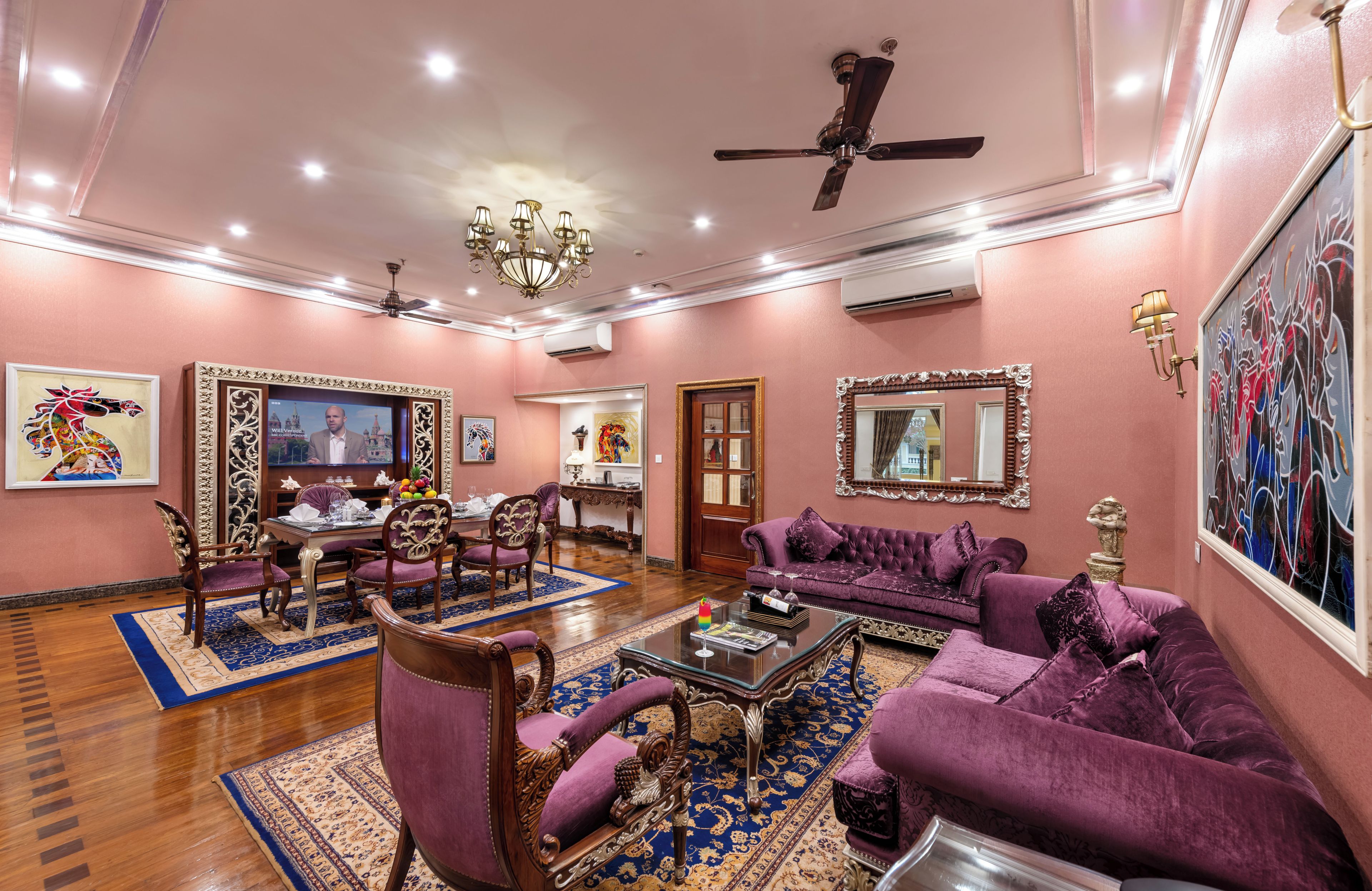 A spacious living room with a chandelier, purple sofas, and a coffee table.