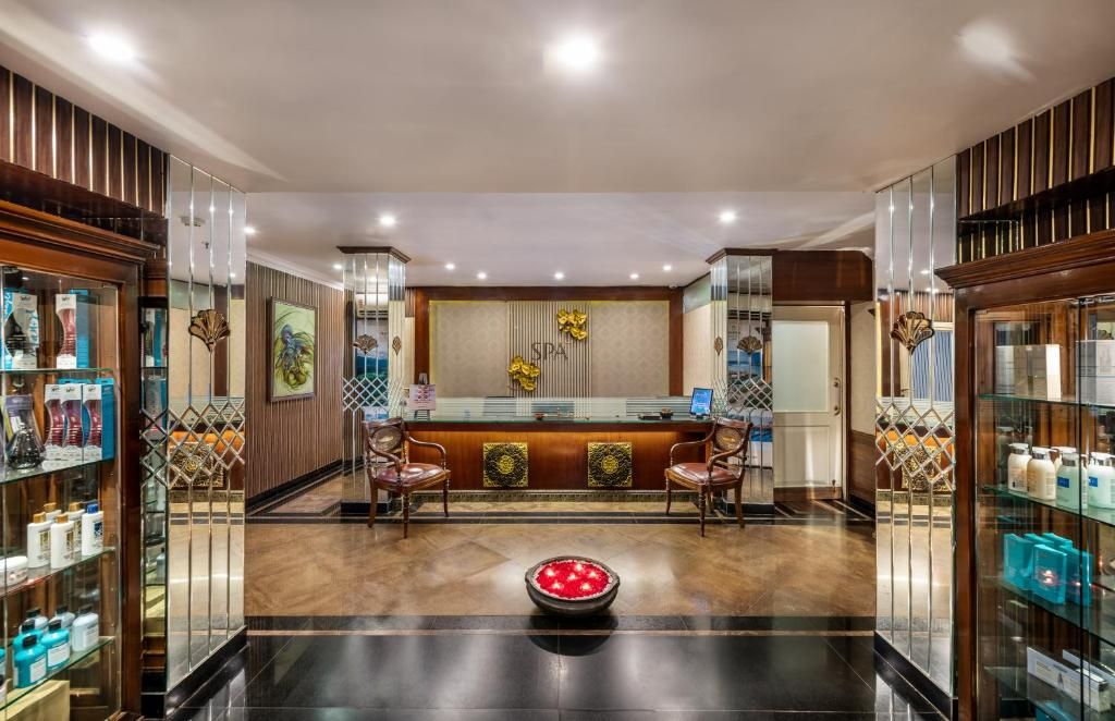 Un área de recepción con mostrador, dos sillas, un cuenco decorativo y vitrinas de vidrio con productos.